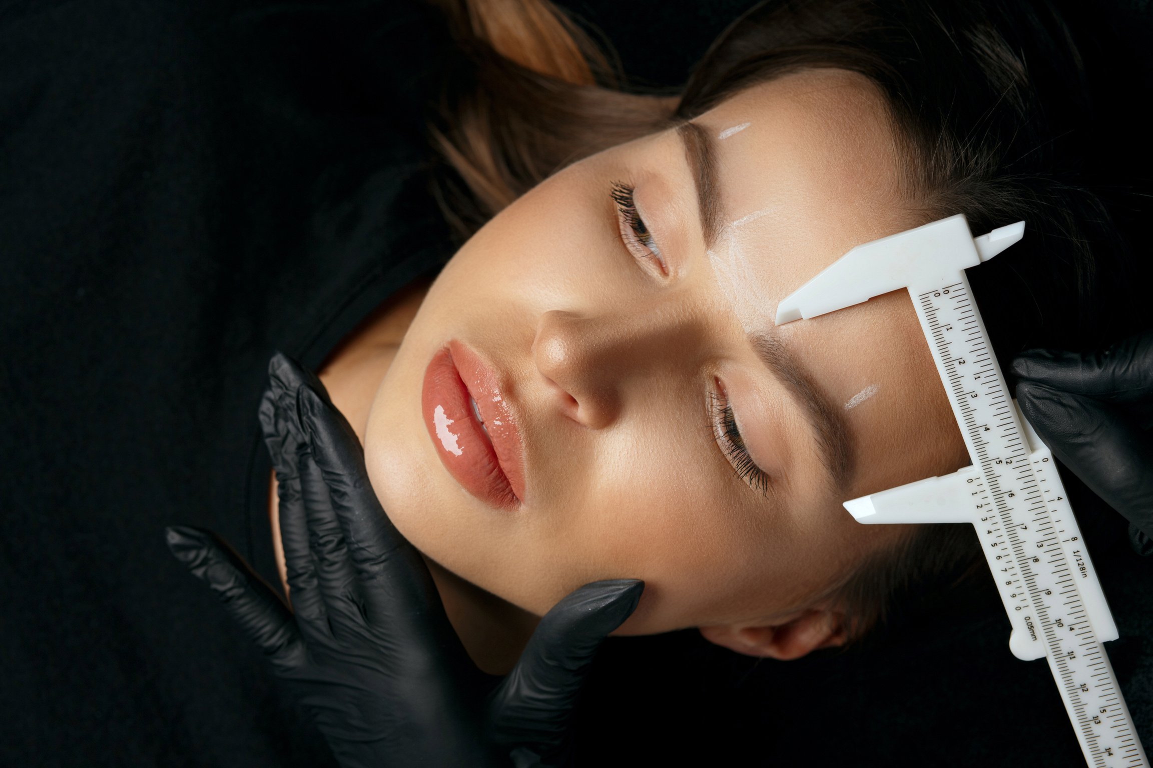 Cosmetician makes measuring before brow tattoo